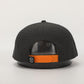 Black cap with orange strap on a light gray background